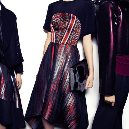 Three models in navy and burgundy outfits, one with a striped pleated dress and black clutch, against a white wall, for Aldo.