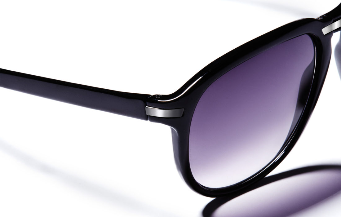 Close-up of glossy black sunglasses with purple gradient lenses and silver hinge accents on white, for H&M.