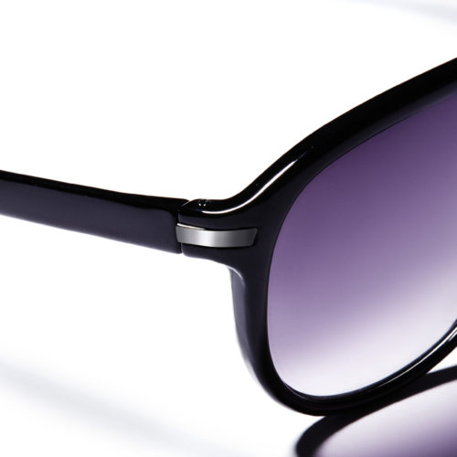 Close-up of glossy black sunglasses with purple gradient lenses and silver hinge accents on white, for H&M.