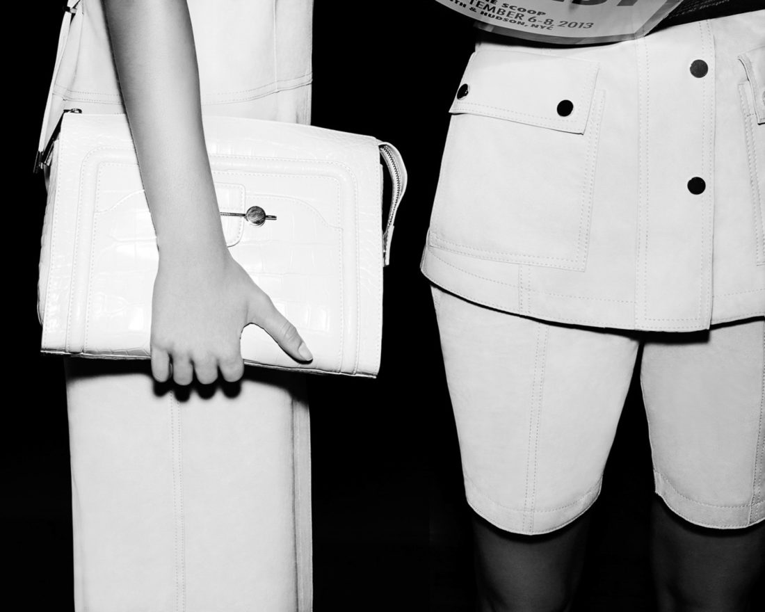Black-and-white backstage shot of models in white leather, one holding a croc-embossed clutch, for Jason Wu.