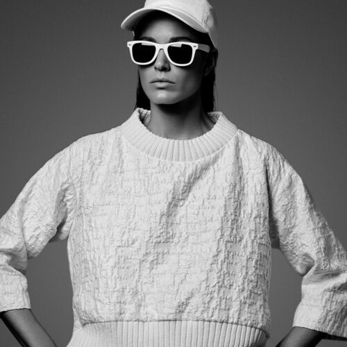 Black-and-white portrait of Chiara Baschetti in a white cap, white sunglasses and textured cropped sweater.