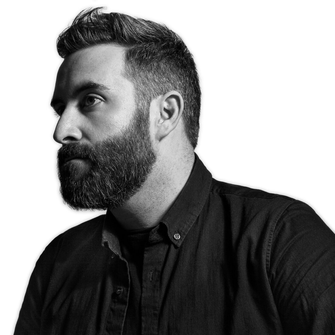 Black and white profile portrait of Michael Kagan, bearded, in a dark button-down shirt against a white background.