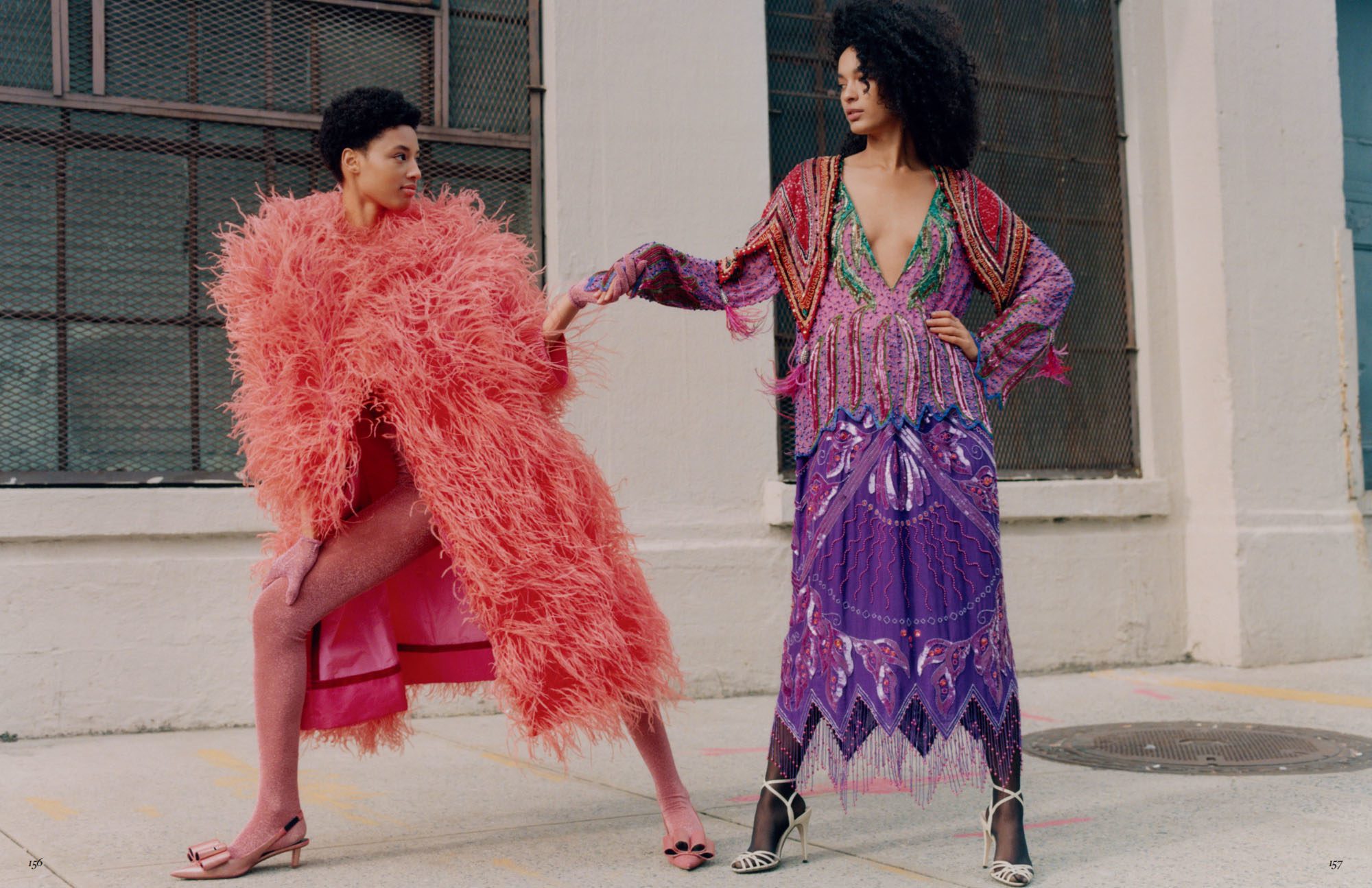 Two models on a city sidewalk, one in a coral feather coat, the other in a purple beaded fringe dress, for Vogue Mexico.