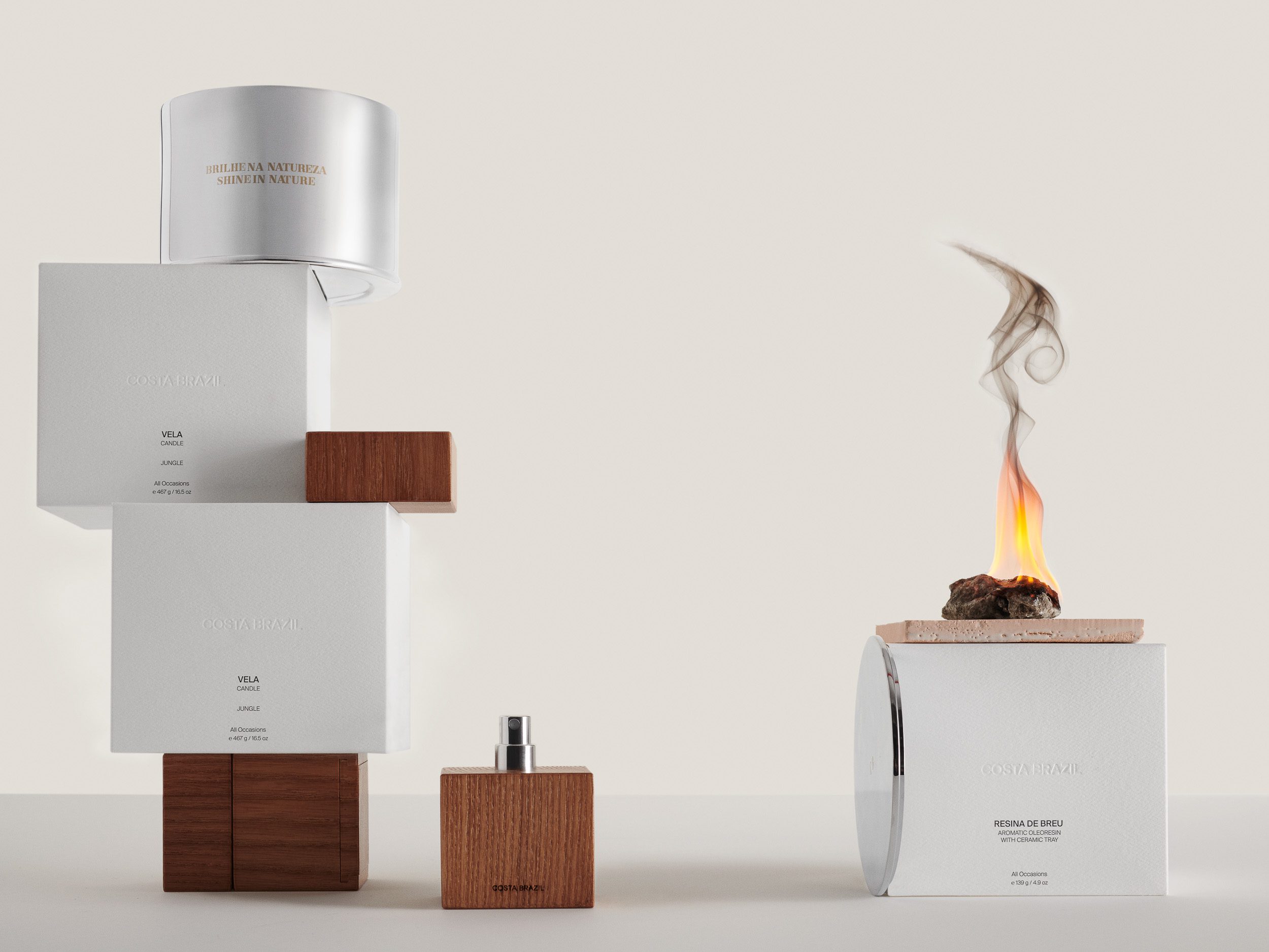 Still life of white candle boxes stacked on wood blocks, a wooden perfume bottle and burning resin with smoke, for Costa Brazil.