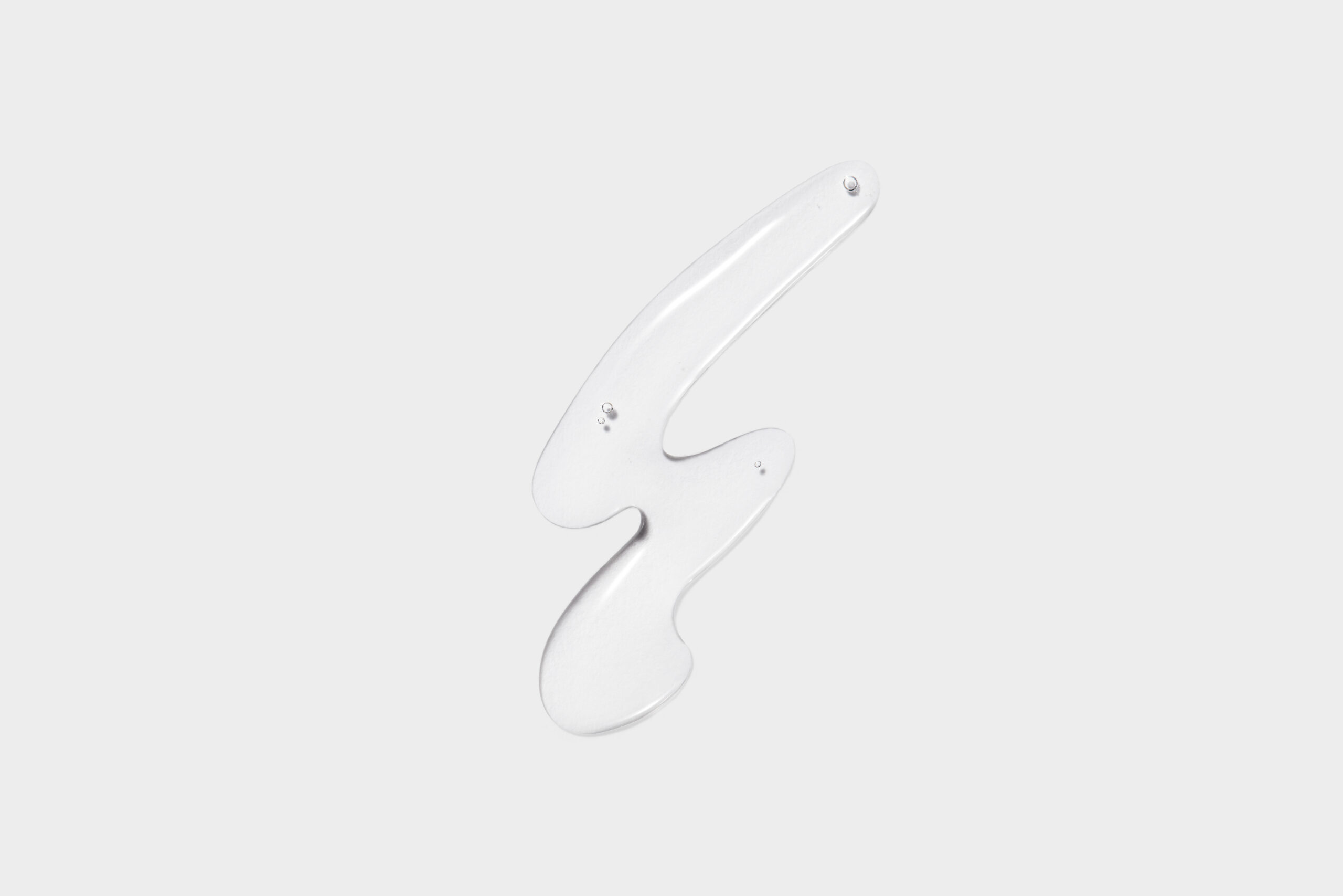 Swirl of clear gel with small air bubbles on a pale grey background, a still life, for Costa Brazil.